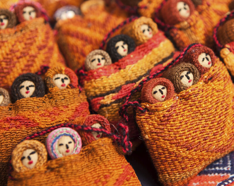 Colorful woven fabric dolls on display.