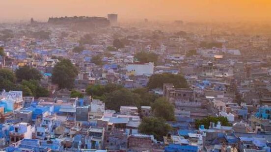 Aerial view of a dense cityscape with blue buildings at sunset.