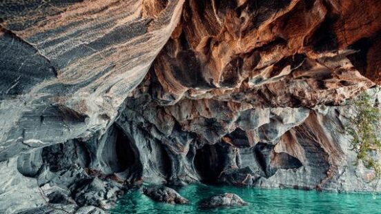 A cavern with striated rock walls above crystal-clear turquoise water.