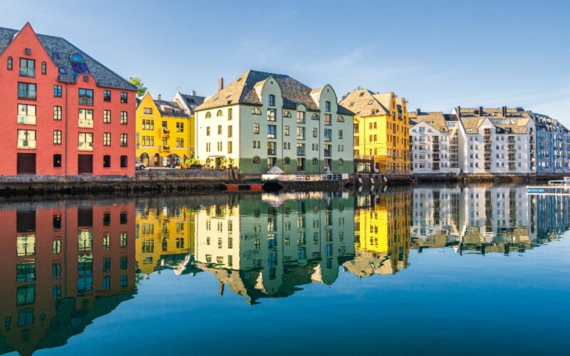 Colorful buildings reflecting in water under a clear blue sky.