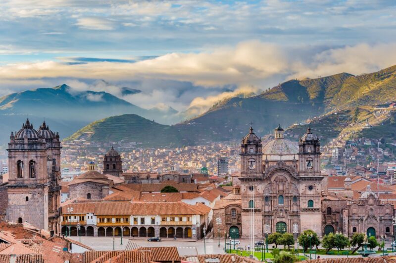 Cusco's historic center with colonial architecture and mountainous backdrop at dusk.