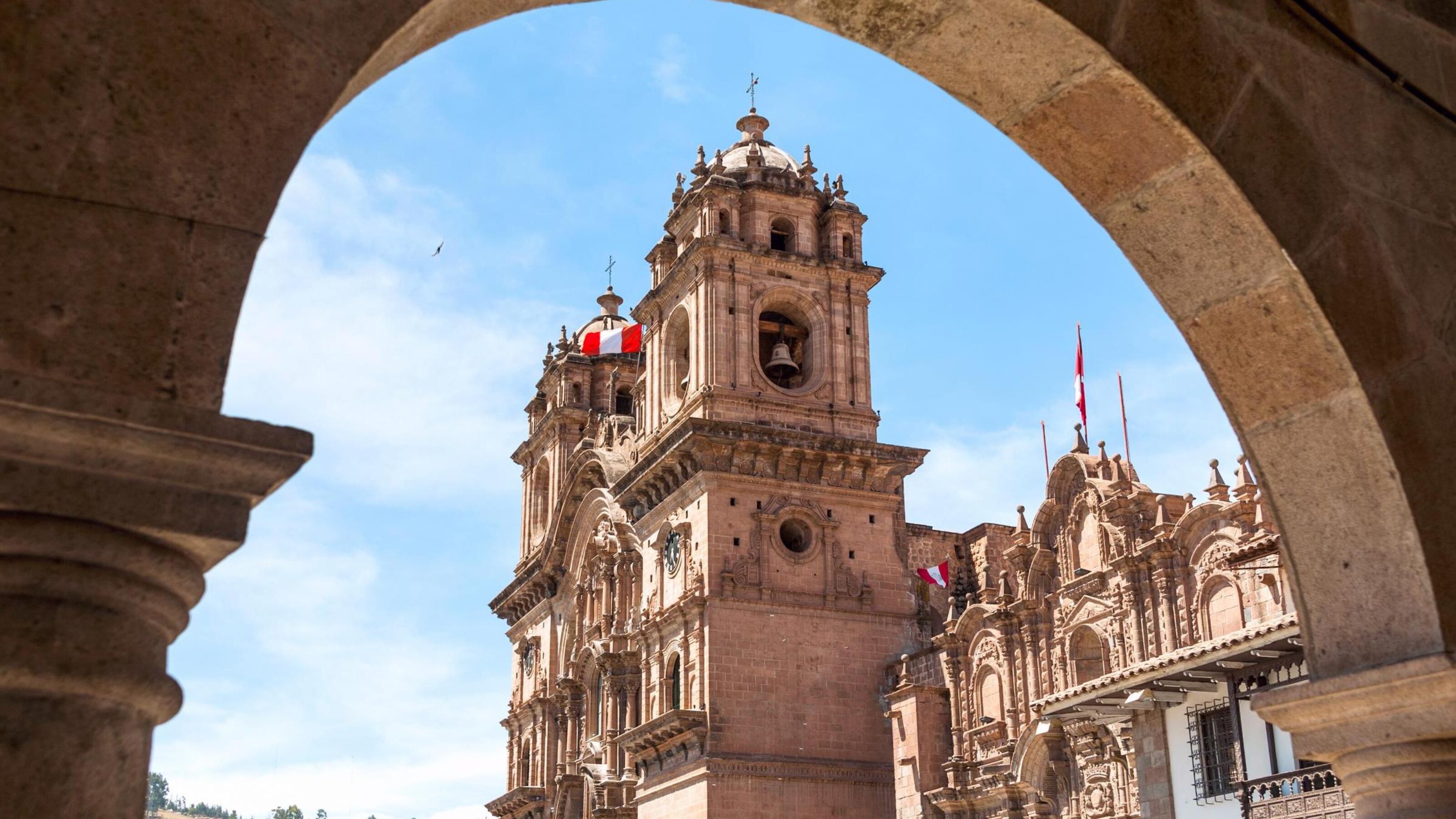 Colonial-style cathedral viewed through an archway against a blue sky.