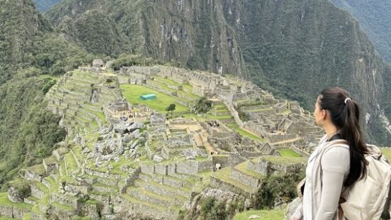 A person admiring the ancient Machu Picchu ruins amidst mountainous terrain.