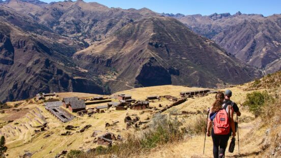 A man and a woman trekking past Incan ruins on the Inca Trail, Peru