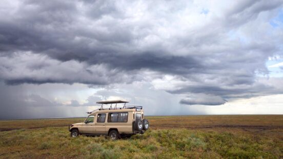 A safari jeep under cloudy skies in Africa