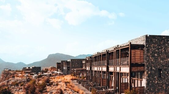 Modern buildings blending with rugged desert landscape under a clear blue sky.