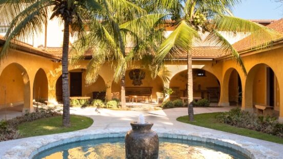 Courtyard with fountain, palm trees, and archways in a sunny villa.