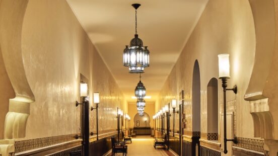 Elegant corridor with arched ceiling, hanging lanterns, and benches along the walls.
