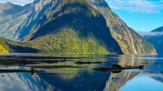 Mountain peak reflecting on a calm lake with clear blue skies.