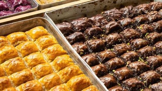 Assorted trays of baklava with different fillings and toppings.