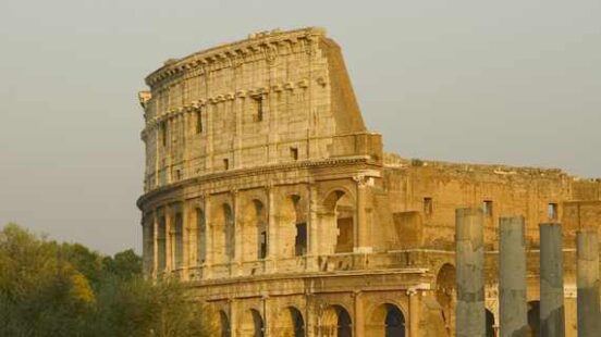 Sunset light on the Colosseum with ancient ruins in foreground.