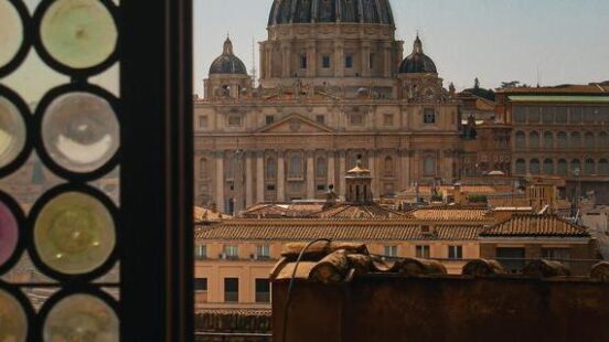 View of a domed cathedral through a window with decorative glass circles on the left.