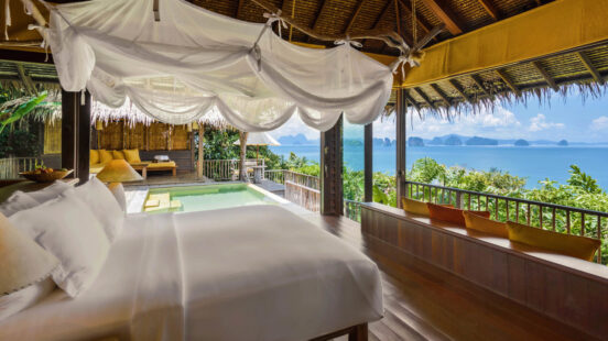 Luxury tropical resort room with a bed facing an ocean view, balcony, and private pool.
