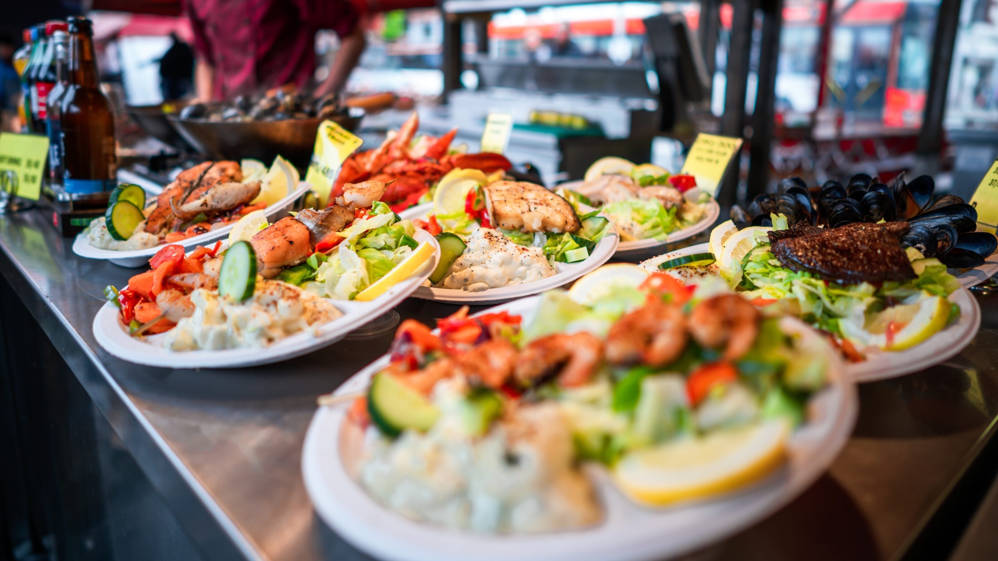 A colorful display of seafood platters, featuring shrimp, fish, and salad garnished with lemon and fresh vegetables on a serving table.