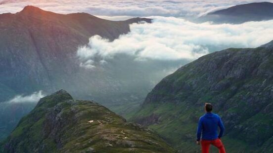 A man watching sunrise over the mountains in Glen Coe, Scotland