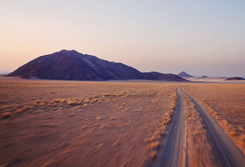 Off road dirt tracks in motion early morning desert scene with mountain and clear sky Wolwedans Namib Desert Rand Nature Reserve Dark Sky Reserve Namibia Southern Africa