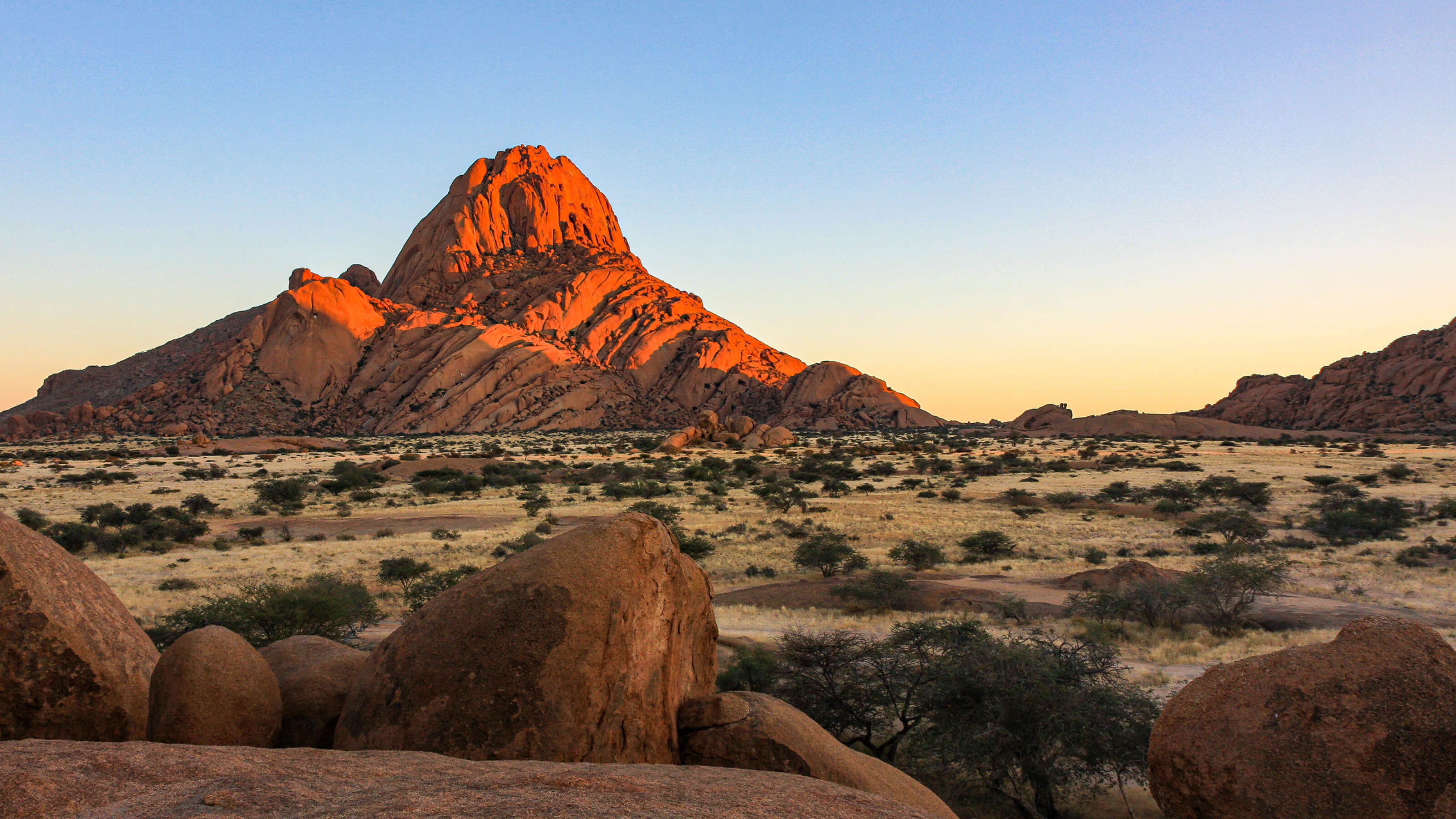Sunlight paints the Spitzkoppe mountain in Namibia rich shades of orange.