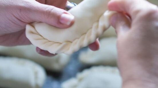 A womanx27;s hands making empanadas