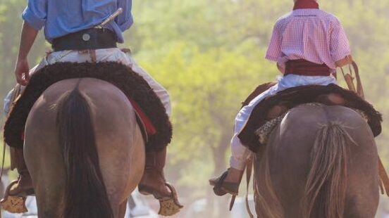 An adult gaucho riding side by side with a child