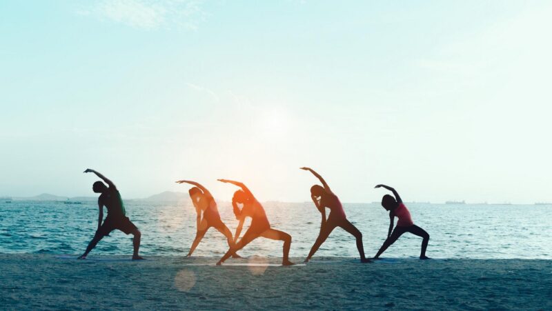 A group of people doing yoga on the beach