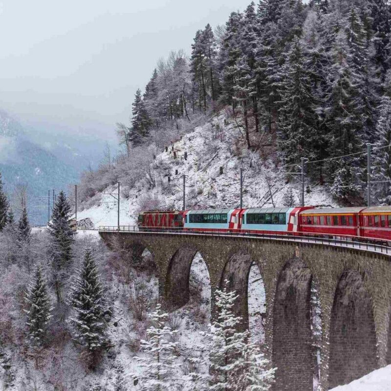 The Glacier Express train travelling across a snowy bridge in Switzerland
