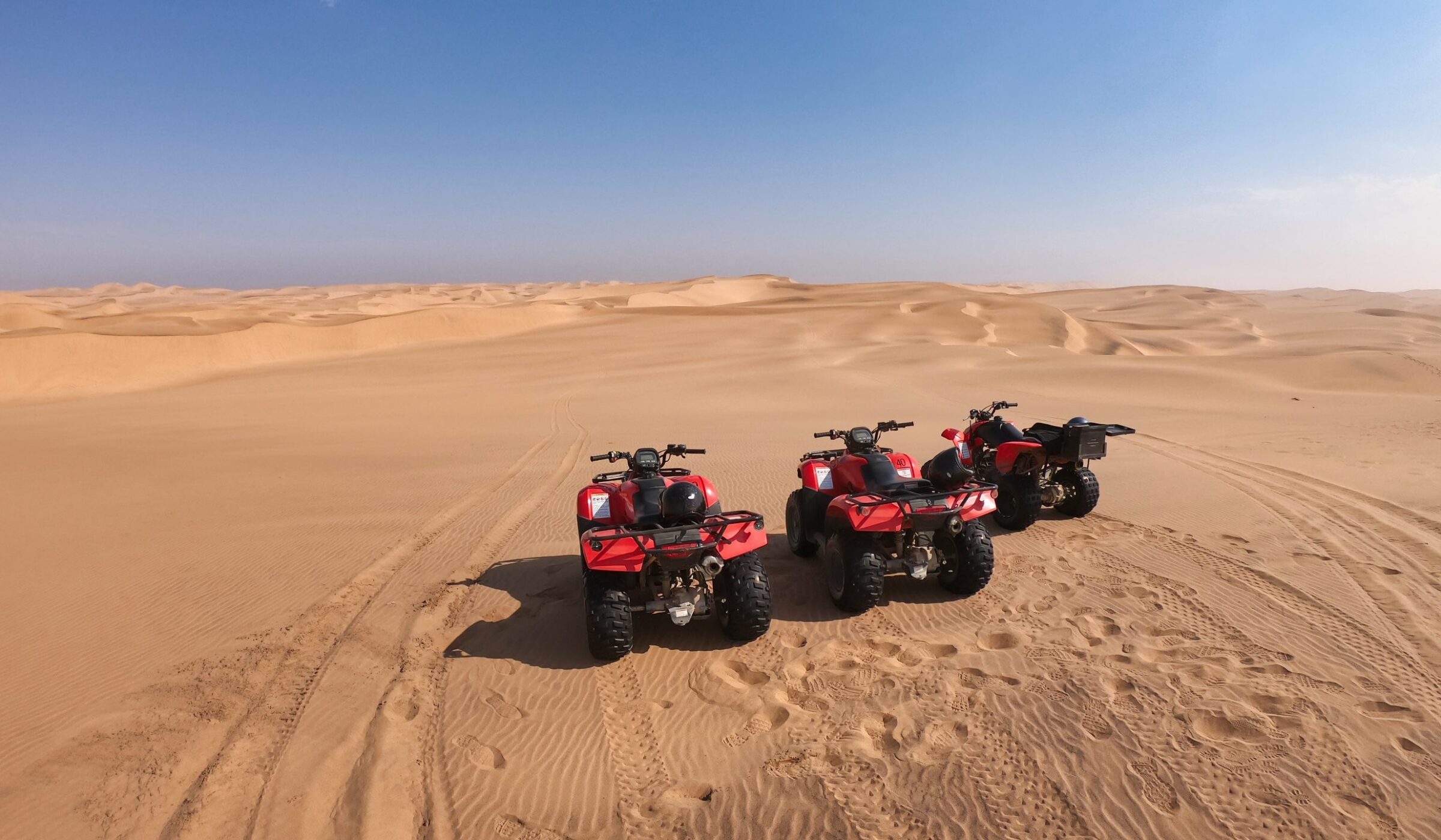 Three quad bikes parked side by side in the desert