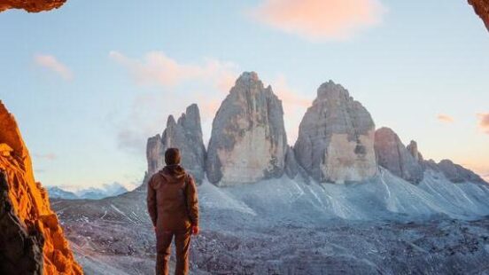 A man stood in front of the Tre Cime Di Lavaredo peaks in the Dolomites