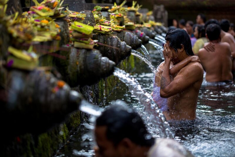 People washing their faces at a water purification ceremony in Ubud, Bali