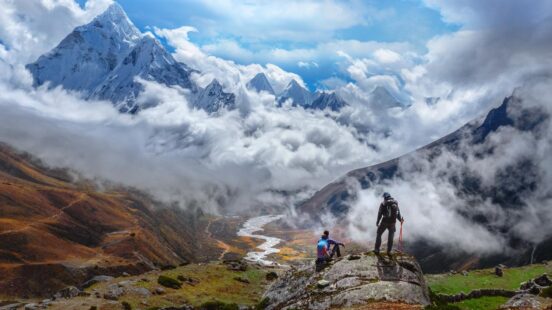 Active hikers hiking, enjoying the view, looking at Himalaya mountains landscape.Tracking to Everest base camp valley with Ama Dablam view. Travel sport lifestyle concept
