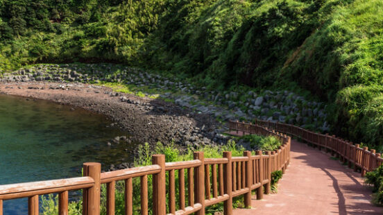 South Korea Pathway leading to beach with view over ocean and Ilchulbong Seongsan Jeju Island South Korea