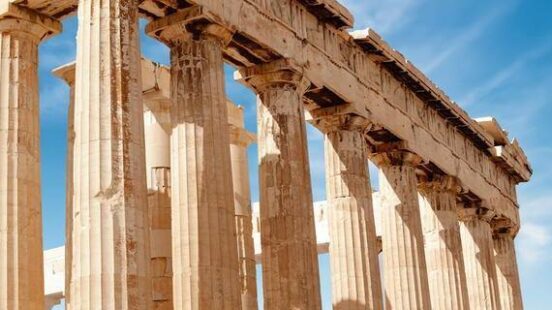 Doric columns of the Parthenon reaching into a clear blue Athenian sky.