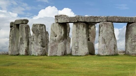 Neolithic sarsen stones of Stonehenge standing against a bright Wiltshire sky.
