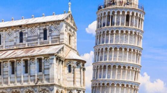 Intricate Romanesque marble arcades of Pisax27;s leaning bell tower against a vivid sky.