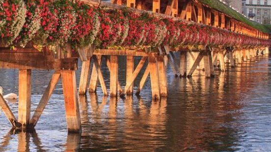 Flower-draped timber frame of Lucerne’s Chapel Bridge spanning the Reuss River.