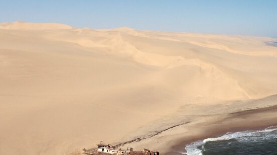 A shipwrecked boat left between the land and sea of The Skeleton Coast in Namibia