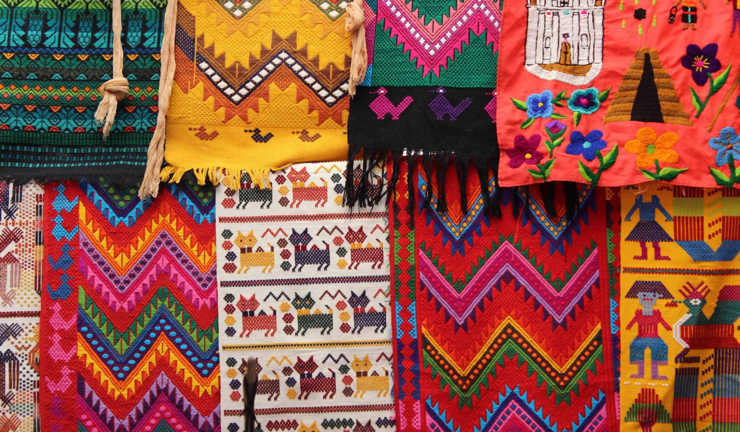 Close-up of vibrant, richly colored Guatemalan textiles hanging together with geometric and figurative woven patterns.