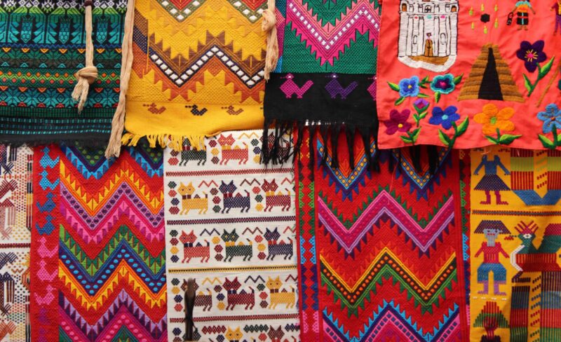 Close-up of vibrant, richly colored Guatemalan textiles hanging together with geometric and figurative woven patterns.