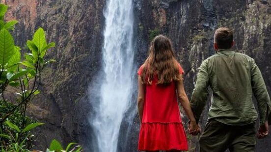 Couple stand beneath Australiax27;s largest waterfall, Wallaman falls in Queensland