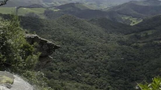 Slow-mo aerial video of a red-tinted waterfall in Ibitipoca jungle.