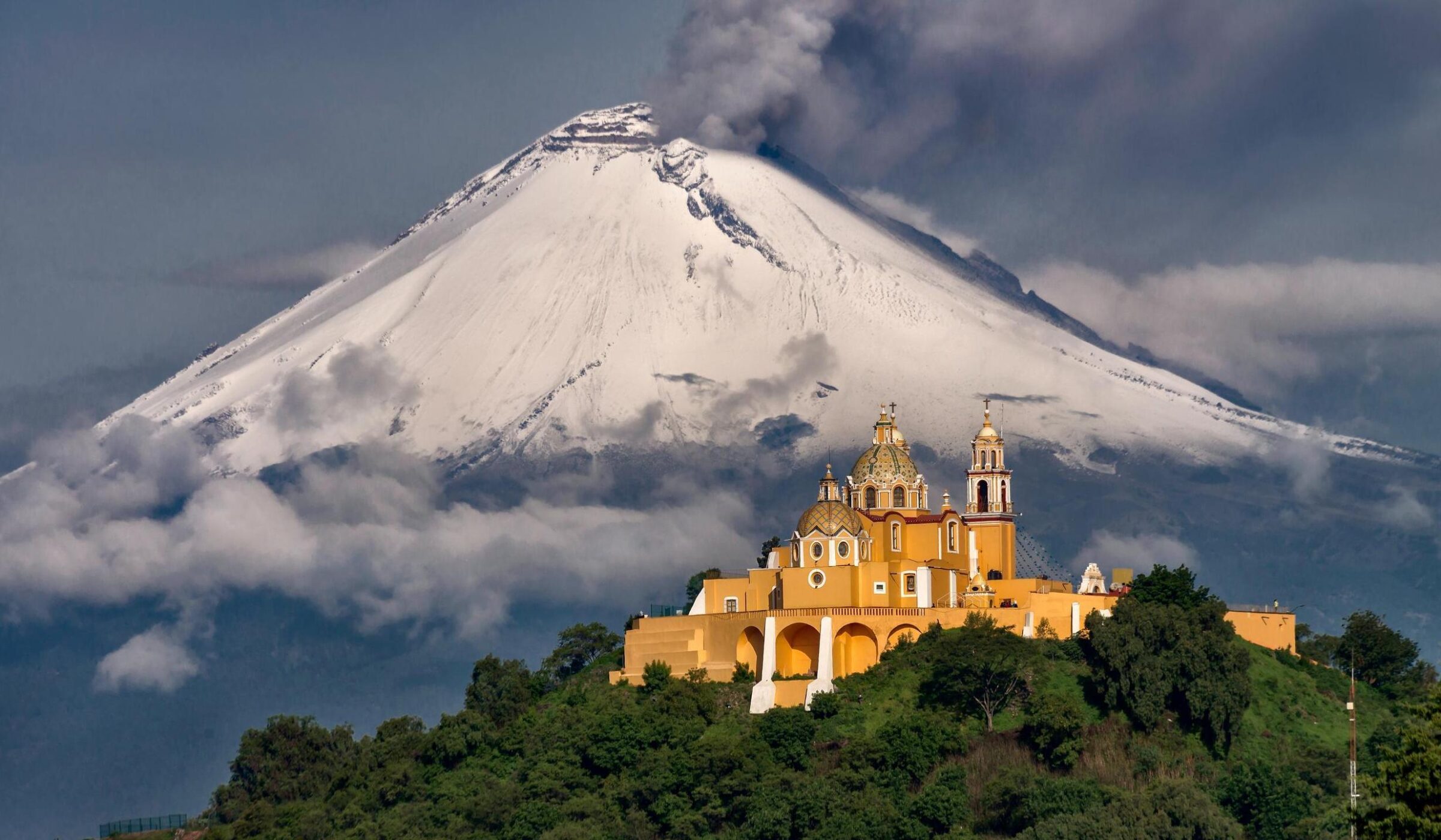 Morning view of church in Puebla, Mexico, and a volcano behind with snow