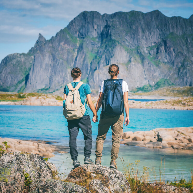 Two woman stand holding hands in Norway's Lofoten Islands