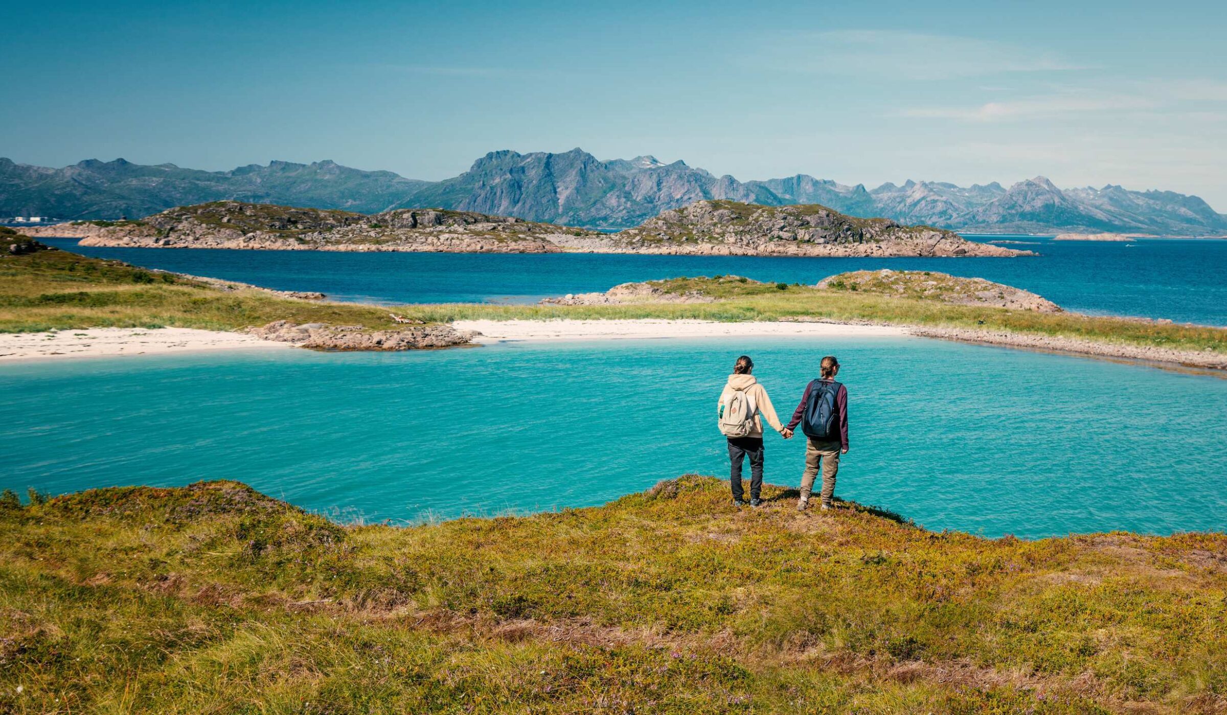 LGBTQ+ trips - Two women hold hands and admire the view of a lake while hiking