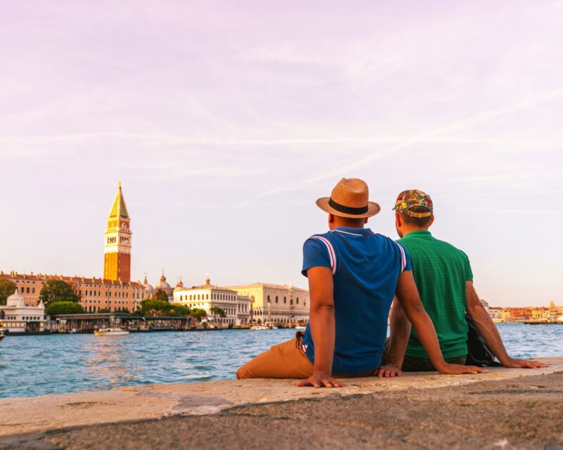 A couple sit by the canal in Venice to admire the view