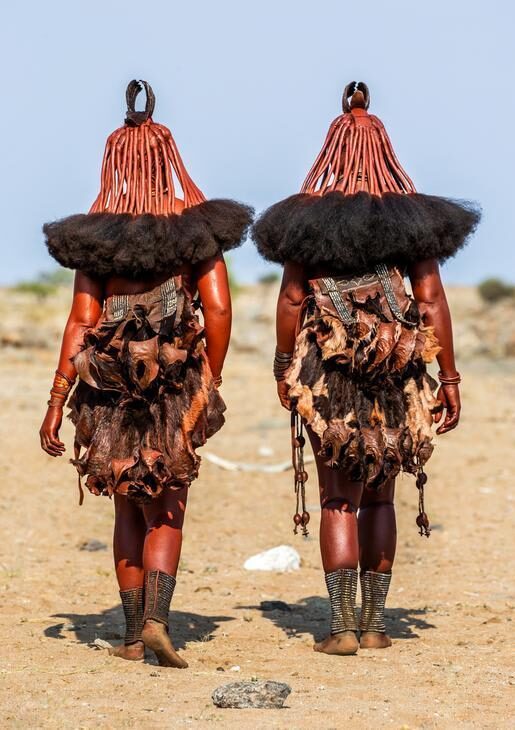 Rear view of two Himba women walking in a desert during positive impact tours.