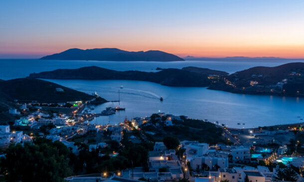 Dusk settles over Yialos harbor in Ios and twinkling lights frame the Aegean Sea.