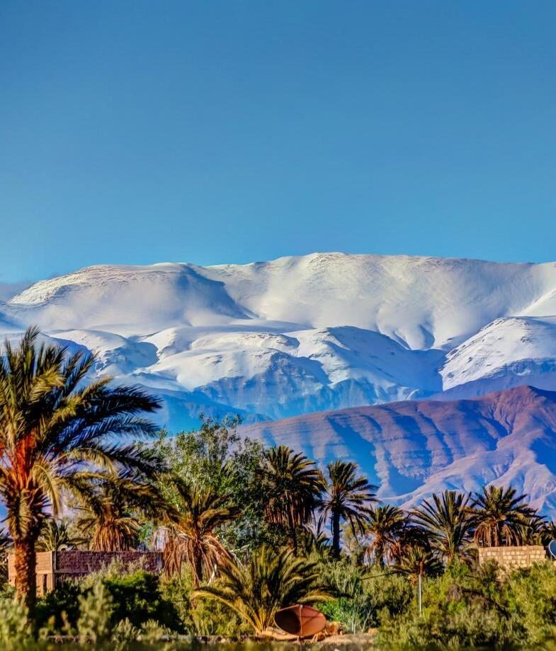 Snow-capped peaks of the Atlas Mountains rising above Morocco’s desert and terraced vineyards lining the Douro River in Portugal’s valley region.