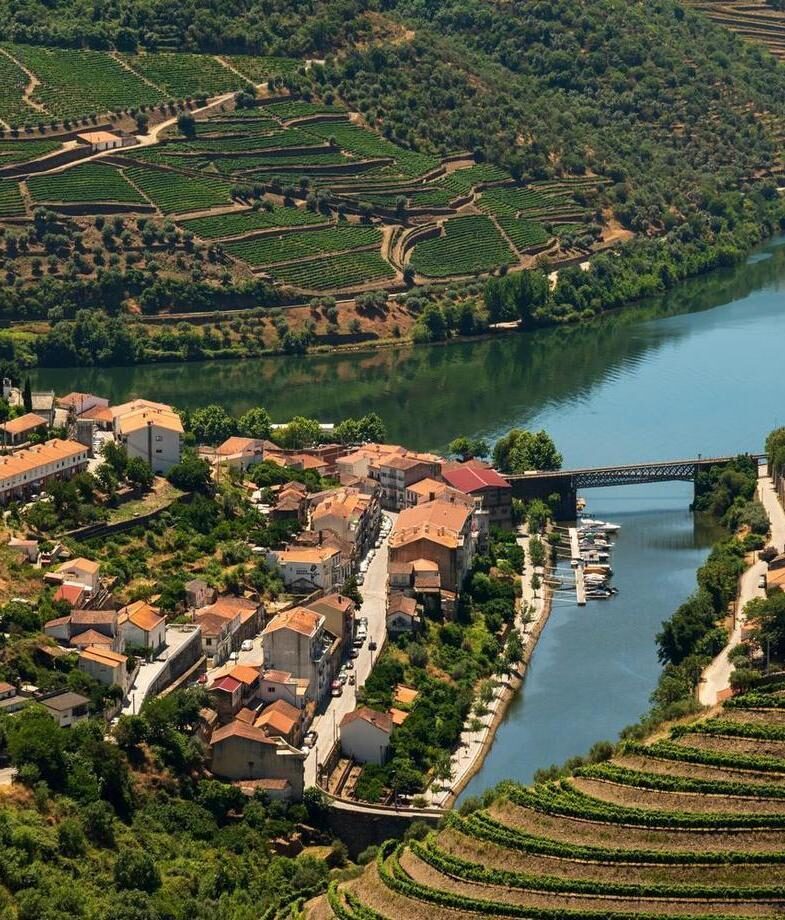 Snow-capped peaks of the Atlas Mountains rising above Morocco’s desert and terraced vineyards lining the Douro River in Portugal’s valley region.