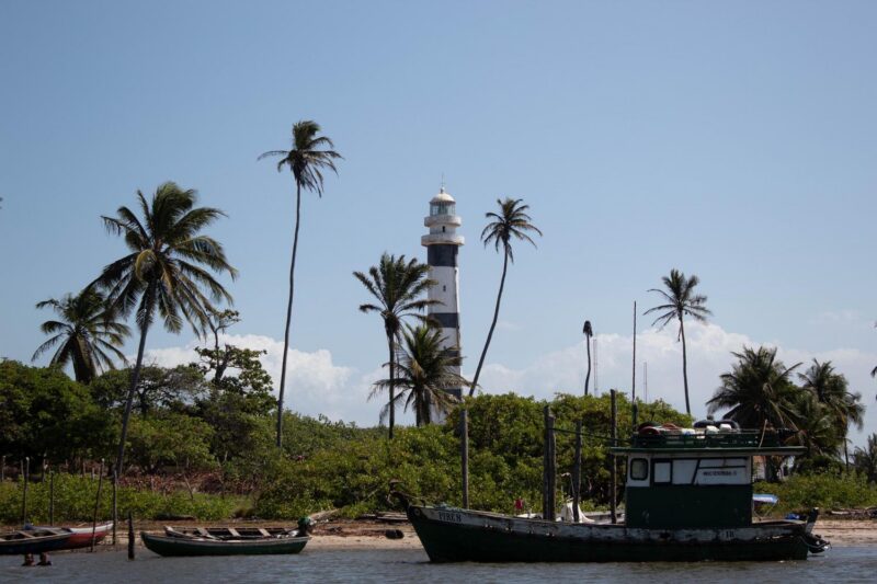 Lighthouse and palm trees with a boat on Preguiças River