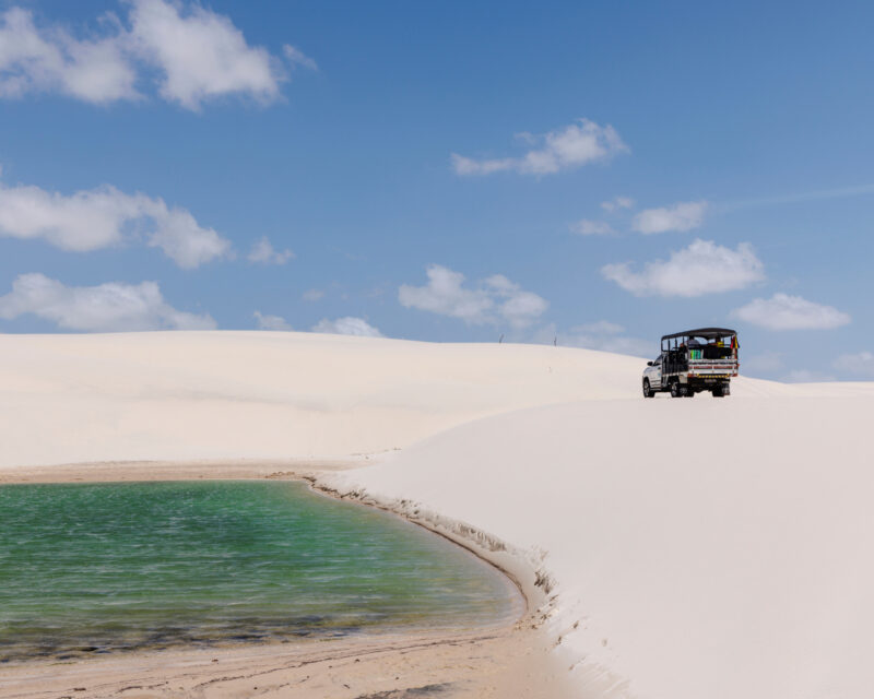 A jeep driving across the sand dunes at Lençóis Maranhenses