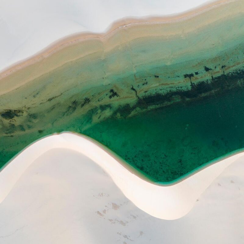 Aerial view of sand dune and green lagoon at Lençóis Maranhenses